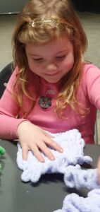 Kind leert breien zonder naalden met Puffy lusjesgaren.